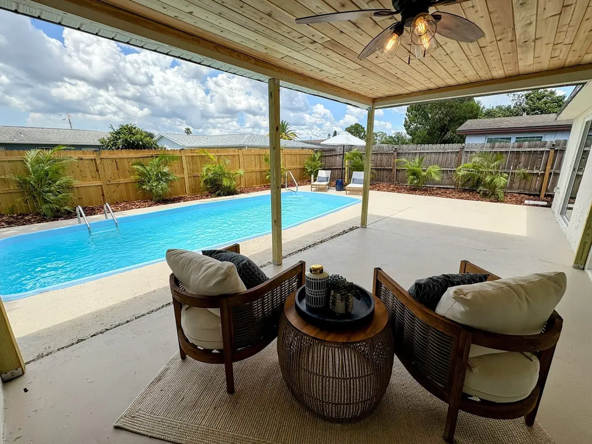 Lounge chairs under a covered patio looking out to a sunlit pool